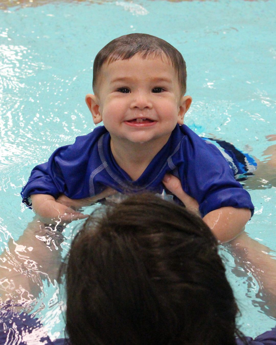 A happy baby enjoying a swimming class